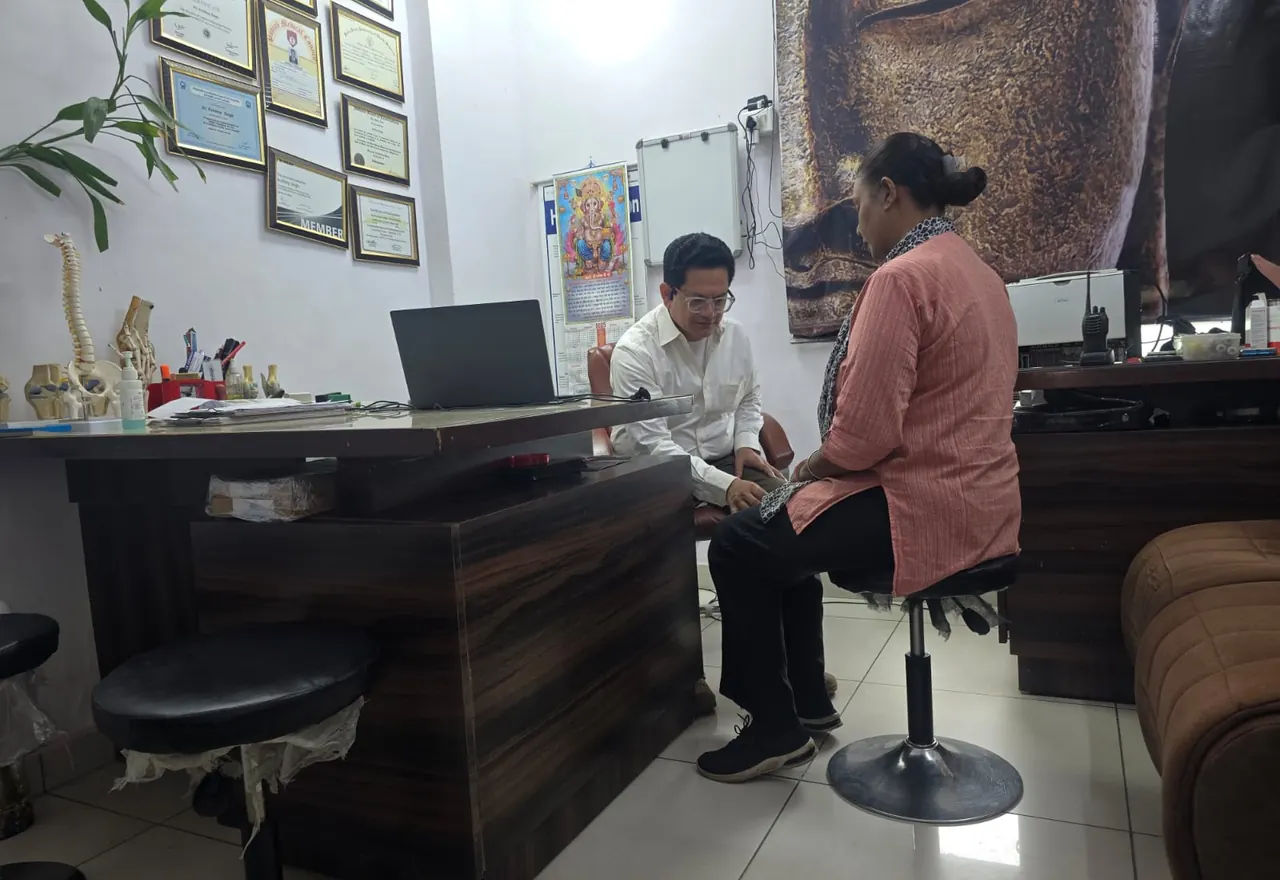 Dr. Kuldeep Singh examining a patient's knee in his consultation room